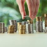 cropped view of person stacking coins on table, investment concept